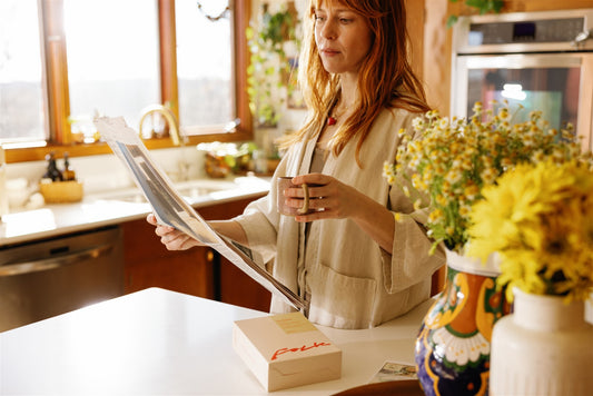 Morning coffee and the newspaper at the kitchen counter, a Folk box beside her